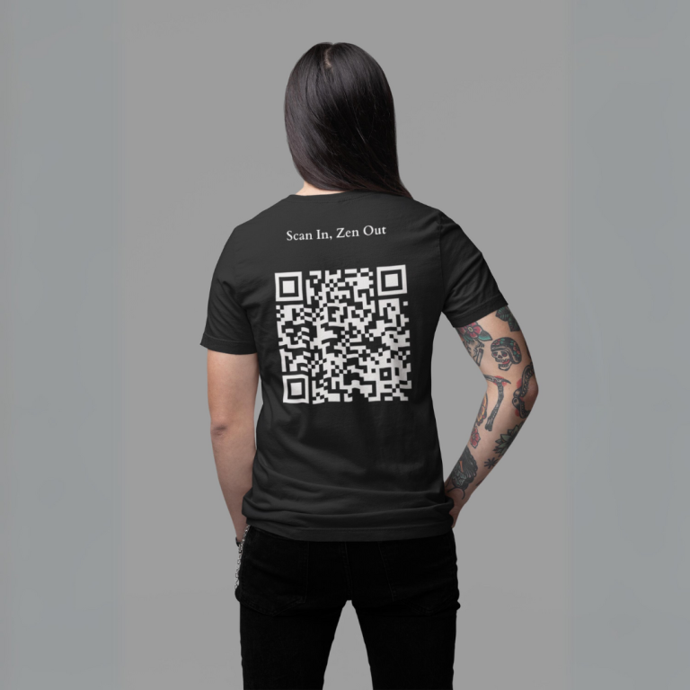 A person with long, straight hair wearing a black t-shirt with "Scan In, Zen Out" and a QR code on the back looks off to the side against a gray backdrop.