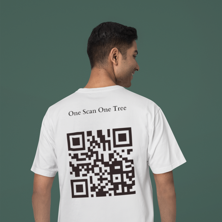 A man stands with his back to the camera, wearing a white t-shirt with a QR code and the message "One Scan One Tree" on the back, set against a dark green backdrop.